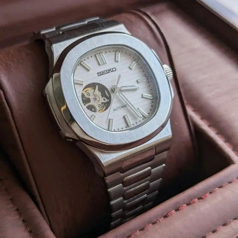 Montre automatique de style Nautilus — configuration cadran blanc à cœur ouvert (NH38) avec cadran blanc, lignes horizontales, vue en biais côté gauche dans une boîte
