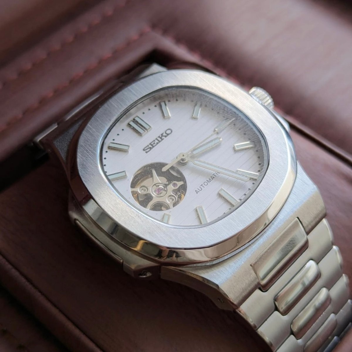 Montre automatique de style Nautilus — configuration cadran blanc à cœur ouvert (NH38) avec cadran blanc, ouverture ronde du cadran, vue macro du côté gauche