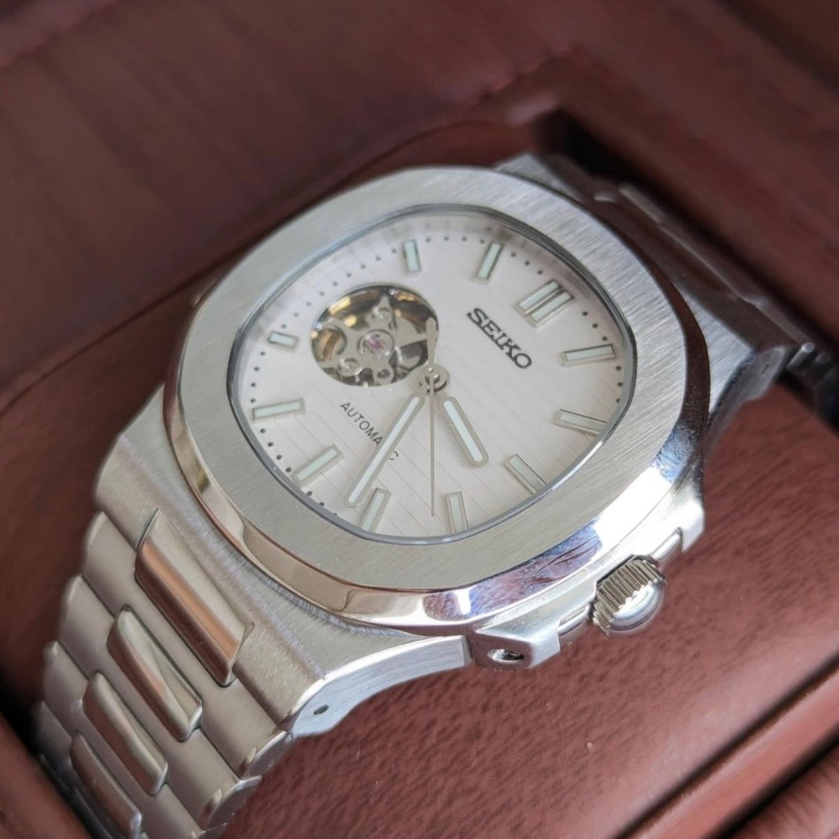 Montre automatique de style Nautilus — configuration cadran blanc à cœur ouvert (NH38) avec boîtier aux tons argentés, couronne striée, vue macro du côté droit