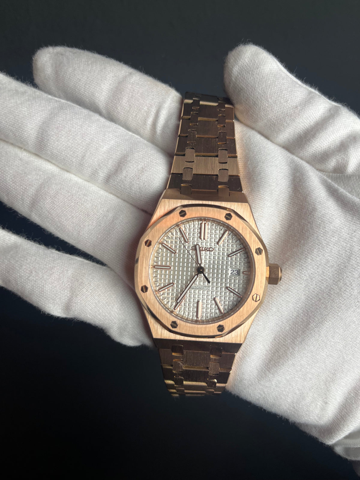 Montre automatique ModTime de style Royal Oak — configuration aux tons or rose et blancs (NH35), cadran blanc, guichet de date, tenue avec des gants blancs