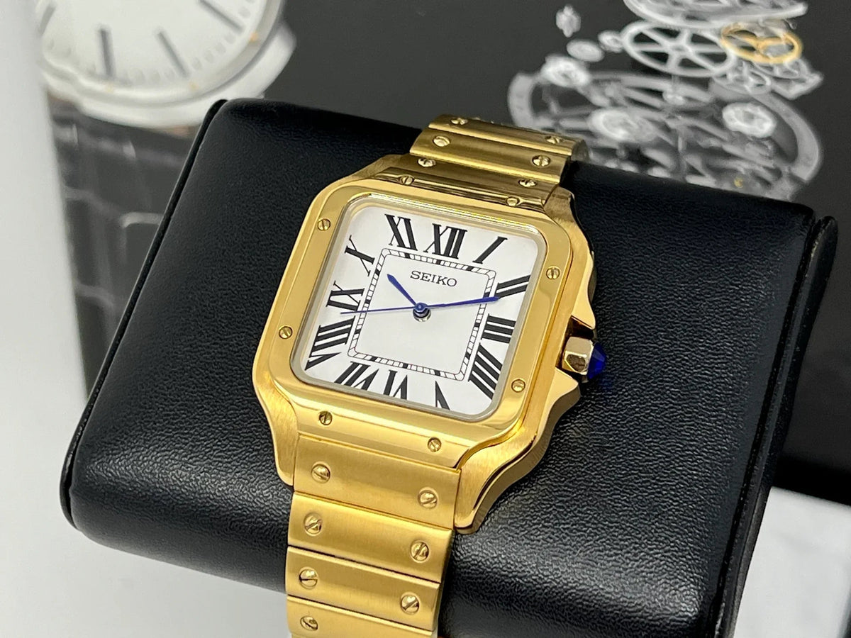 Montre automatique ModTime de style Santos — configuration aux tons dorés et blancs (NH38), boîtier aux tons dorés, extrémité bleue de la couronne, vue en biais sur un coussin