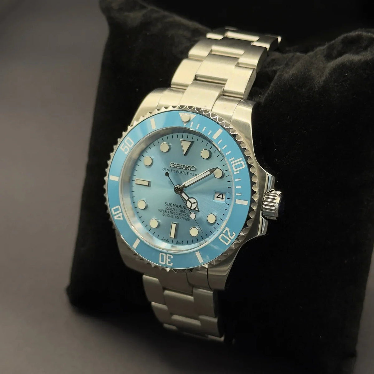 Montre automatique de style Submariner — configuration argentée, cadran bleu ciel (NH35) avec lunette bleue pâle, bord dentelé, en biais sur un coussin