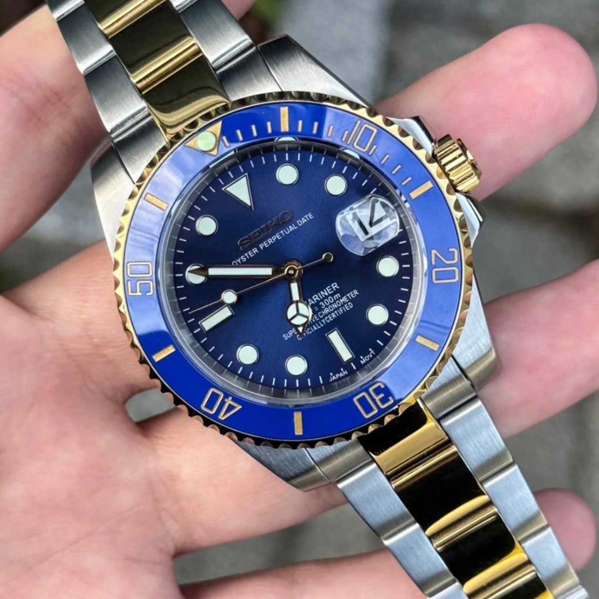 Montre automatique de style Submariner — configuration bicolore, «Ocean» (NH35) avec cadran bleu, aiguilles aux tons dorés, vue de face tenue en main