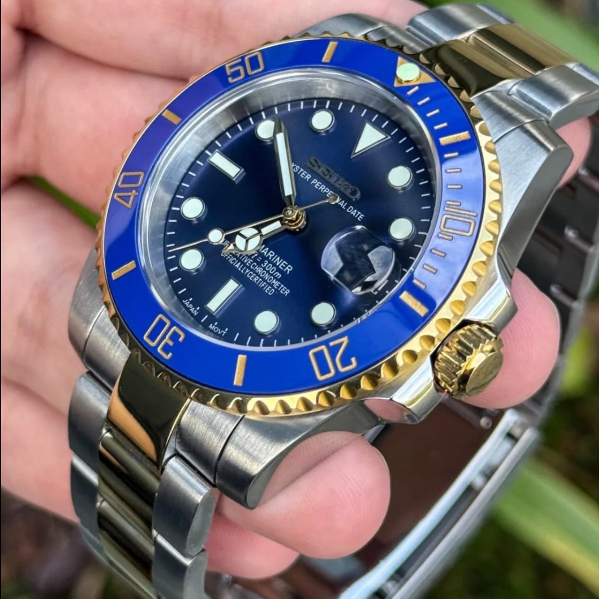 Montre automatique de style Submariner — configuration bicolore, «Ocean» (NH35) avec lunette bleue, couronne aux tons dorés, vue en biais tenue en main