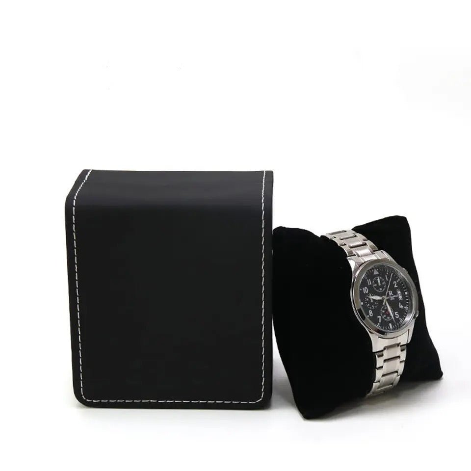 Boîte à montre noire ModTime avec coutures blanches, montre sur un coussin noir séparé à côté, vue en biais