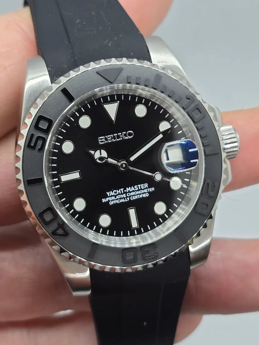 Montre automatique ModTime de style Yachtmaster — configuration cadran noir et bracelet en caoutchouc (NH35), cadran noir, loupe de date, gros plan tenu en main