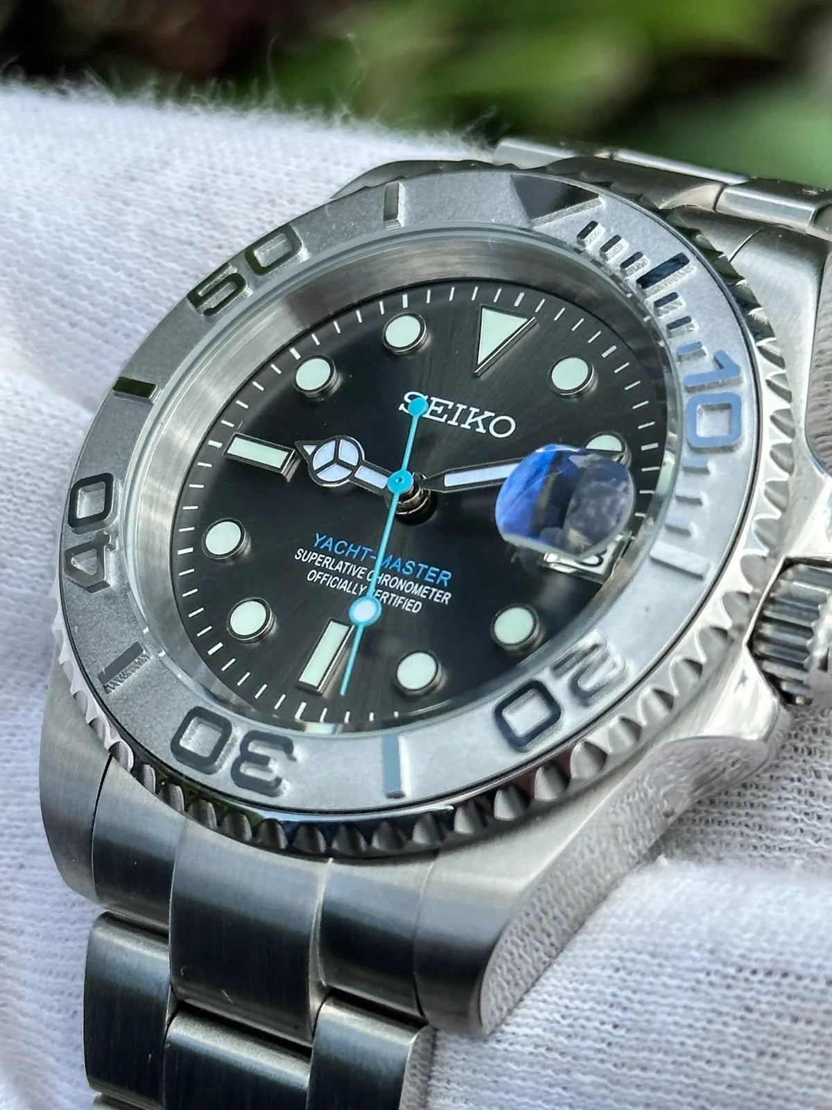 Montre automatique ModTime de style Yachtmaster — configuration cadran gris (NH35), cadran gris, aiguille des secondes bleue, gros plan du cadran tenu dans une main gantée