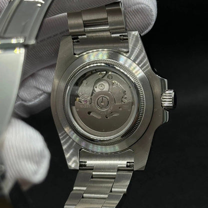 Fiche du modèle ModTime de style Submariner — configuration argentée, «Kermit» (NH35) : boîtier aux tons argentés, rotor portant l'inscription NH35A, vue arrière tenue dans une main gantée